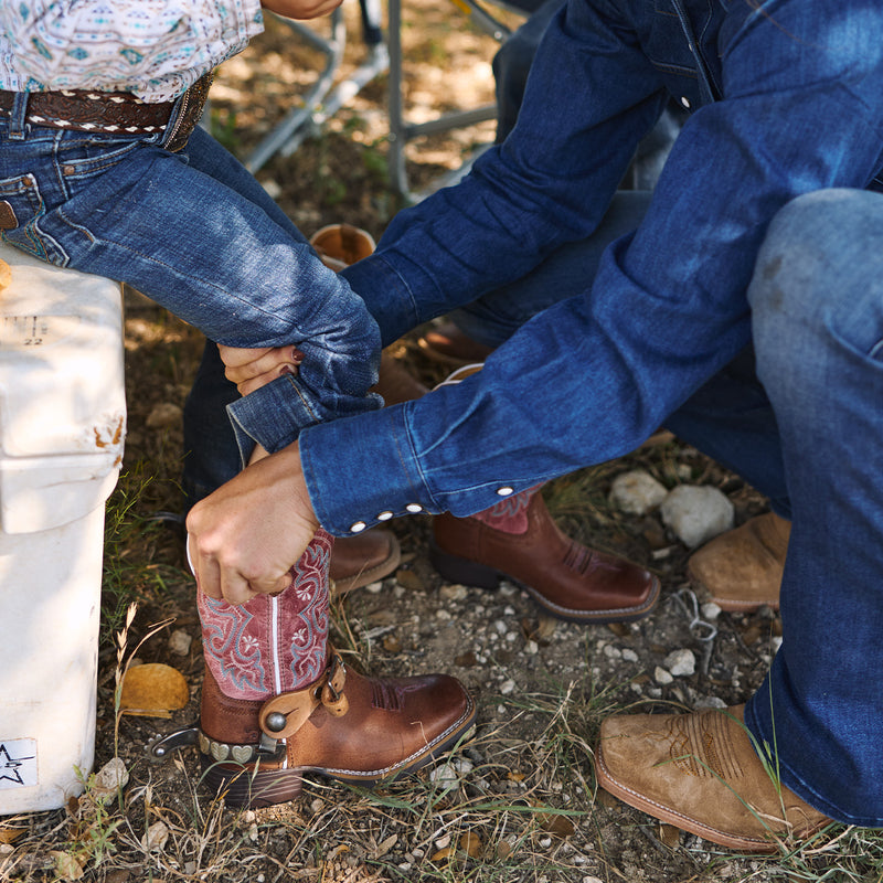 Mom adjusting a kids cowboy boot outdoors