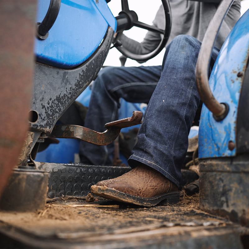 Person operating a piece of heavy machinery with focus on their brown Durango work boots.