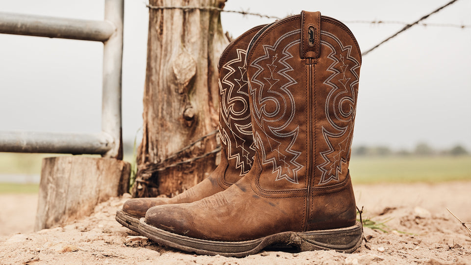Durango brown cowboy boot by a fence gate.