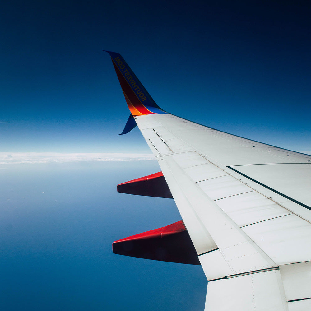 window view of an airplane wing, ocean and blue sky