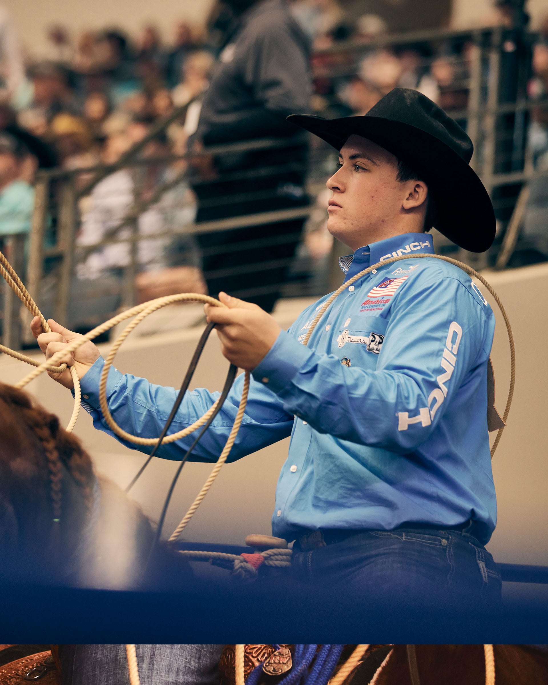 Riley Webb, in a blue shirt holding a lasso at the American Rodeo