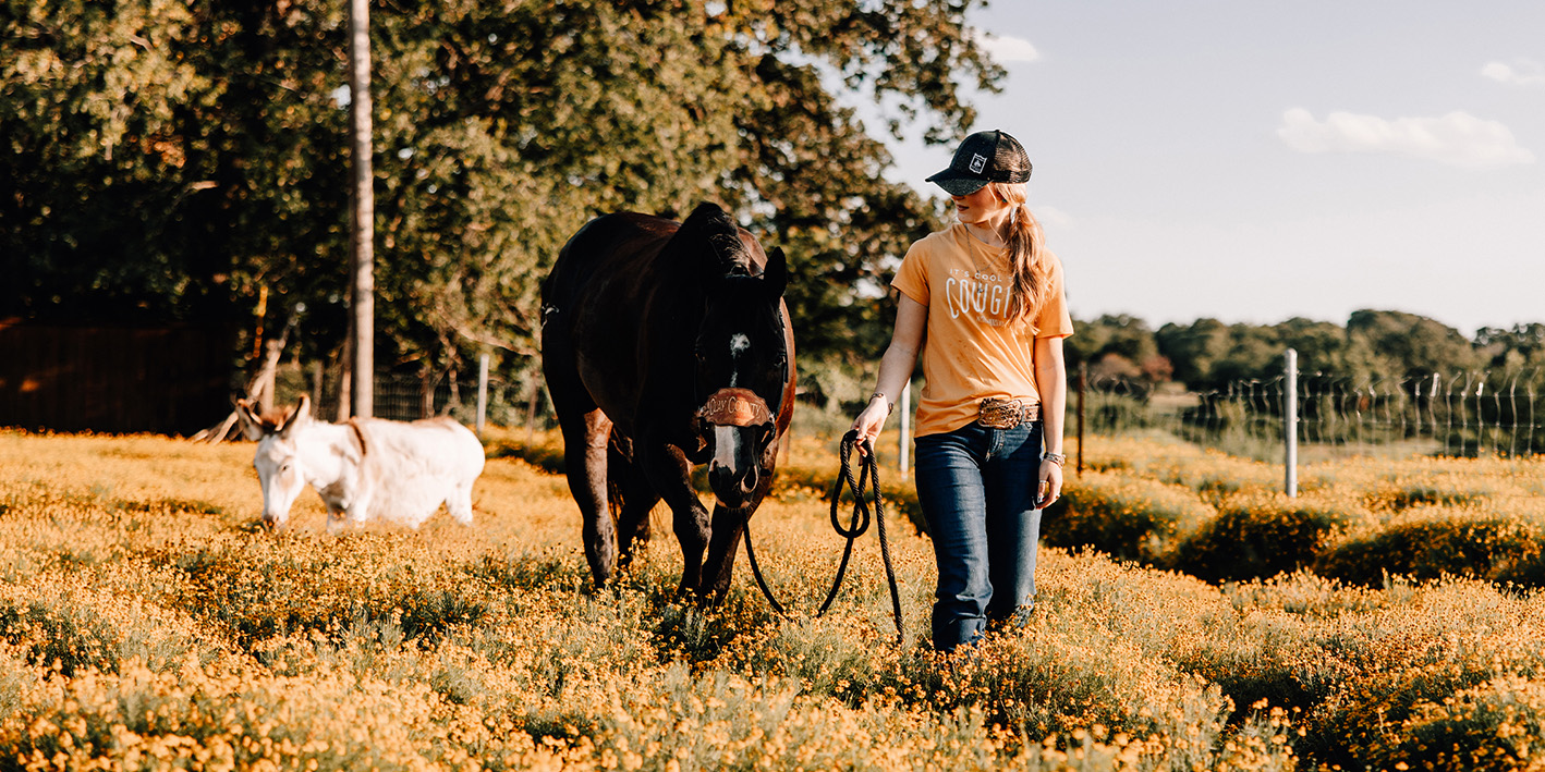 Katelyn Collins and her horse walking through a Texas field.