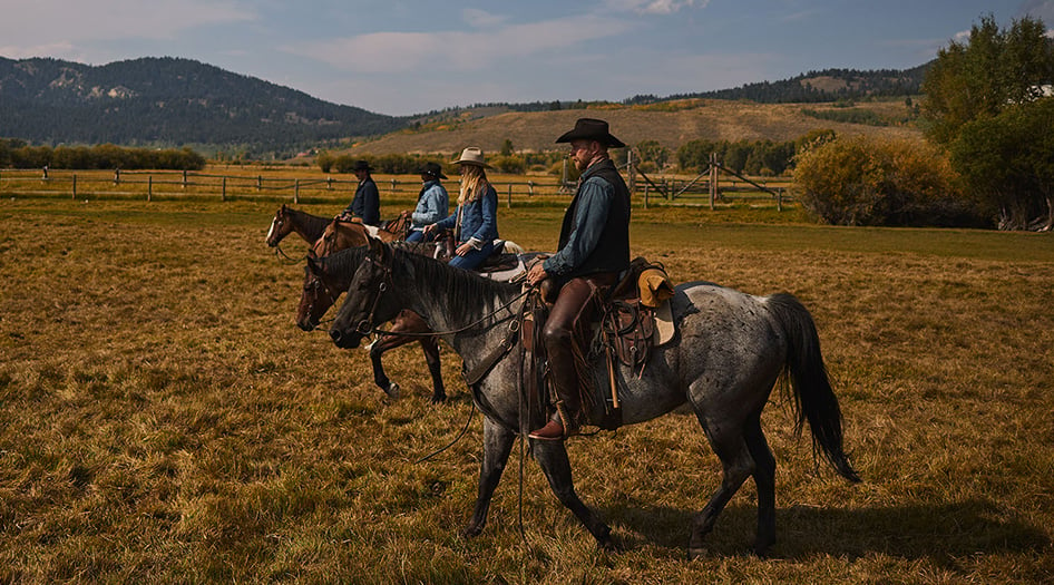 Cowboys and a cowgirl wearing Durango Western Boots while riding horses in Wyoming.